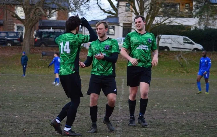 Players celebrating a goal in the green away kit