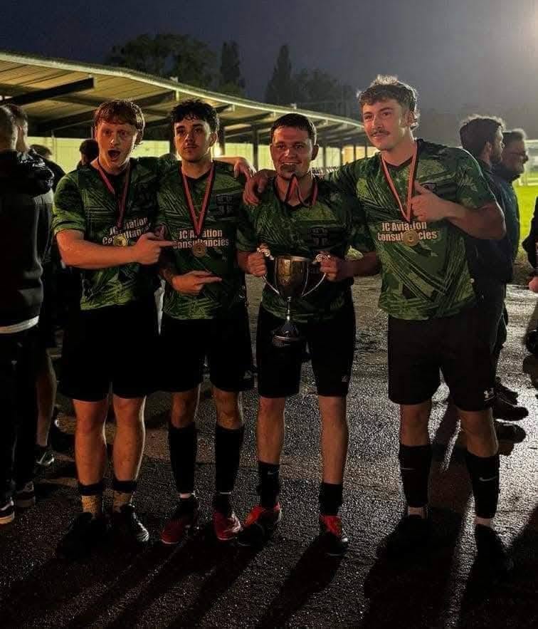 Four Finchampstead United players with the cup and winners' medals under the floodlights